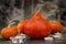 Orange pumpkins and burning candles against a dark stone wall