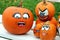 Orange pumpkins with funny drawn ghost faces are on the bench as decoration for outdoor autumn holiday in the park. Funny