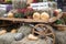 Orange pumpkins on hay, flowers in pots, decorative cartwheel. Autumn street decoration background. Rural market concept