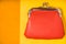 Orange purse on the bright yellow background top view