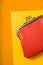 Orange purse with notebook on the bright yellow background vertical