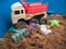 Orange red car truck toys and sand playing shovel with brown sand background.