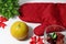 Orange with red kitchen glove and red ribbon and green leaf with dried flower in the glass on white floor