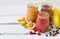Orange, red and purple smoothies of fresh ingredients - bananas, apricots, raspberries and blueberries on a light background. Heal
