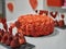 Orange red whipping cream cake decorated with silver edible pearls, black pads with strawberry decorated paper red hearts on white