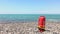 Orange rescue buoy on rocky beach with sea panorama and no lifeguard. Static blank space copypaste background s