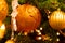 Orange ribbed christmas glass ball and icicle used to decorate spruce tree close up