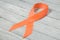 Orange ribbon on wooden background, symbol of the problem of violence against women, kidney cancer association, symbol of