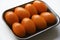 Orange ripe tomatoes on a plastic backing. Delicious tomatoes in a package from the store on a white background. Yellow tomatoes