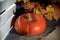 Orange ripening pumpkin near a wooden crate. Lies on a gray background. In the twilight. Nearby are dried autumn leaves and coarse