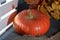 Orange ripening pumpkin near a wooden crate. Lies on a gray background. In the twilight. Nearby are dried autumn leaves and coarse