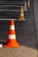 Orange road cones on a asphelt driving area with white lines