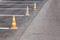 Orange road cones on a asphelt driving area with white lines