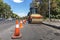 Orange road cones protect heavy wheel compactors along the edge of the city street road