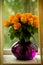 Orange roses in a glass purple vase