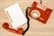 Orange rotary telephone and blank notebook on wooden background