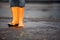 Orange rubber boots in a dirty puddle