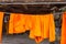 Orange and saffron robes of Buddhist monks hanging on wooden.Thailand.