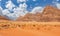 Orange sands and cliffs of Wadi Rum desert with tourist car in background, Jordan