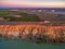 Orange sandstone layers and agricultural fields.