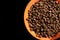 Orange saucer with coffee beans on black background