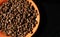 Orange saucer with coffee beans on black background