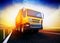 Orange semi-truck on blurry asphalt road under blue sky and suns