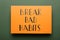 Orange sheet of paper with phrase Break Bad Habits on green background, top view