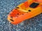 Orange single seater sea kayak for fishing on the pebble seashore