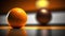 an orange sitting next to an orange on a counter top in front of an orange ball on a table with a li