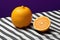 An orange sitting on top of a striped table cloth. AI.