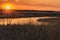 Orange Sky With Setting Sun Over Prairie Grass and River