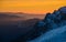 Orange sky and snow powdered mountain slope