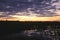 Orange sky sunrise on a dark green wetlands landscape with water reflection and purple clouds