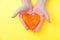 Orange slime in heart shape in kid hands. Girl hands playing slime toy on yellow background. Making slime. Love and