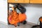 Orange small portable industrial power air compressor with coil hose and pneumatic gun at home warehouse garage under