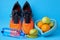 Orange sneakers, measuring tape, water botlle and fruits apples and oranges on a blue background