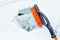 Orange snow brush for car, snowflakes background