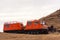 Orange snowcat with second wagon. Another vehicle with snowplow