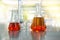 orange solution in flask cylinder vial in science laboratory background