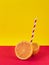 Orange split in half with a straw simulating a soft drink on a yellow and red background
