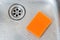 orange sponge and drain of stainless kitchen sink