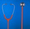Orange stethoscope headset and bell isolated on blue background