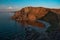 Orange stones rock in light of the setting sun, by the bay with the shore, coast on lake Baikal