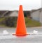 An orange street cone between two small fountains of water