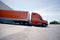 Orange stylish semi truck trailer unloading cargo in warehouse