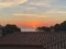 Orange sun circle rising on a coastal landscape on the top of a urban brick roof