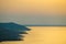 Orange sunset light reflected on sea water near hilly coast