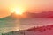 Orange sunset by the ocean in Piratininga, Niteri, with sun dipping behing the Gavea Stone in Rio de Janeiro. A beach full of peop