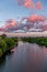 Orange sunset over the city, river, green trees, church.